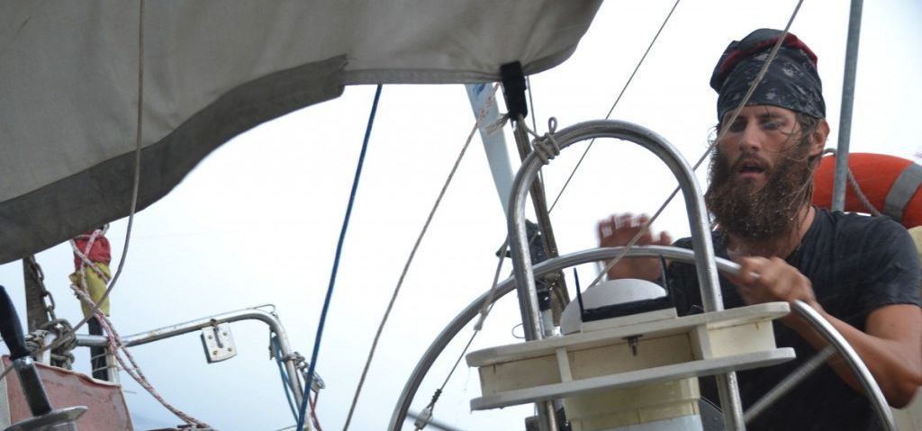 Skipper Ben Schaschek steuert durch einen Sturm. Vor dem Törn hat er nie auf hoher See gesegelt. © sailingconductors.com