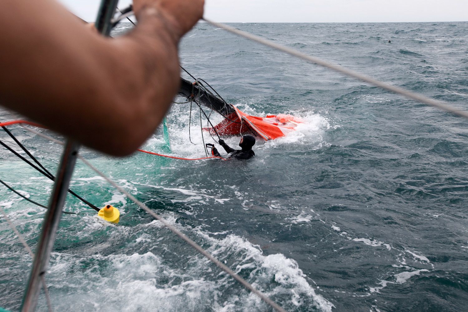Ein Crewmtiglied muss ins Wasser, um die losen Teiel vom Rigg zu schneiden und Schäden am Rumpf zu vermeiden.  © Yann Riou/Groupama Sailing Team/Volvo Ocean Race