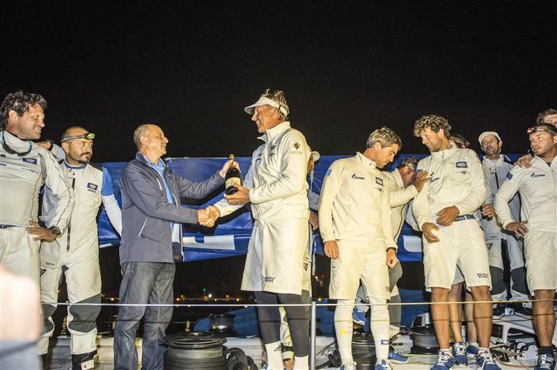 Skipper Jochen Schümann feiert die `First ship home´ Honors mit seiner Crew und Star-Navigator Juan Vila (links). © Rolex / Kurt Arrigo