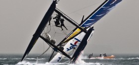 Red Bull geht kopfüber. Die behelmte Crew klammert sich am Trampolin fest. © Lloyd Images/Extreme Sailing Series