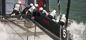 Russell Coutts bleibt mit seinem Bugspitzen in einer Welle hänge. Das Heck hebt sich, die Ruder ragen aus dem Wasser. © Guilain Grenier/Oracle Racing