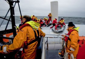 Die irischen Retter bergen die einzelnen Crewmiglieder mit einem Gummiboot vom umgedrehten Rumpf der "Rambler". © RNLI