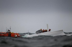 Die "Rambler"-Crew hat sich auf das umgestürzte Schiff gerettet und hält sich am Canard fest. © Richard Langdon