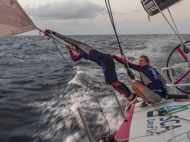 Annie Lush hält Justine Mettraux fest als sie eine neue Genua-Schot anbringt. © Corinna Halloran/Team SCA Volvo Ocean Race