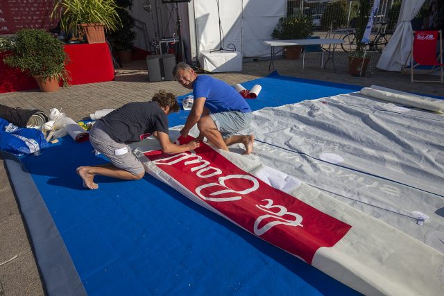 Der deutsche Teilnehmer bei den Serien Minis Hendrik Witzmann – etwas angespannt beim Bekleben seines Großsegels mit dem MTA-Logo © breschi, mini transat Mini Transat, Vorbereitung, La Rochelle